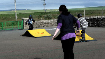 Three children on roller blades at the skate park
